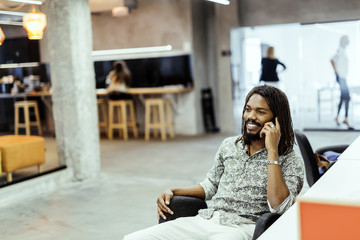 Handsome black man using phone in office
