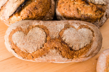 homemade rustic rye bread with hearts pattern on a light wooden background, flat lay. Rustic style