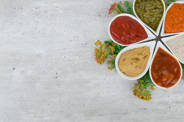Top view on a set of tasty sauces with a copy place and fresh herbs.