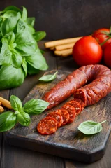 Poster Chorizo sausage. Spanish traditional chorizo sausage with fresh herbs and tomatoes, selective focus. © julijadmi