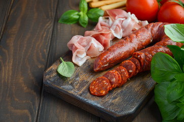 Chorizo sausage. Spanish traditional chorizo sausage and ham with fresh herbs and tomatoes, selective focus, copy space.