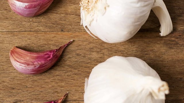 Slowly panning over fresh ripe garlic bulbs on a wooden chopping board