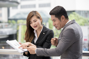 Happy businessman interesting for woman present project with him. Preple working at outdoor place.