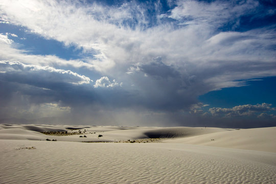 white sand desert with hills and dunes and a stormy and cloudy sky