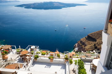 Fira, Thira town, Santorini, Cyclades islands, Greece. Beautiful view of the town with white buildings, blue church's roofs and many colored flowers.