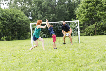 Cheerful family playing football in a park