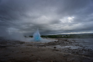 Iceland - Turquoise hot boiling water, beginning of eruption of geyser strokkur with trees