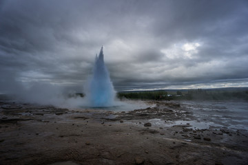 Iceland - Turquoise hot boiling water, summit of eruption of geyser strokkur with trees