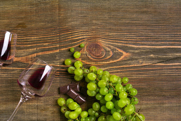 Glasses of wine and ripe grapes isolated on a wooden table