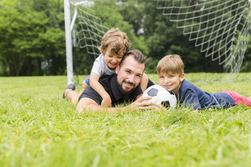 Fototapeta premium Young father with his little son playing football on football pitch