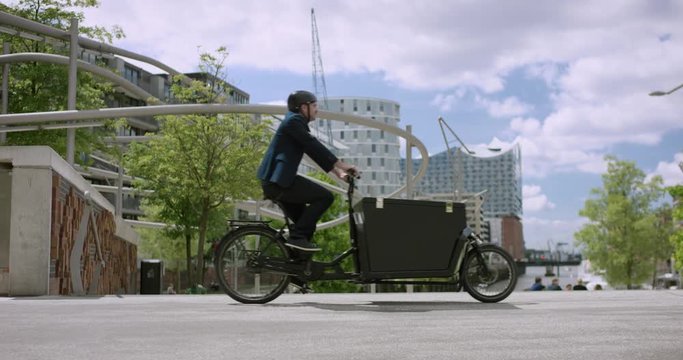 Architect is riding with his cargo bike through the city. Hamburg