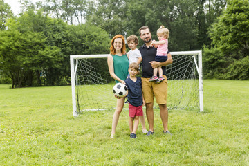 Happy family with football ball on a field