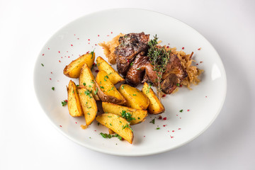 Delicious grilled duck wings with potatoes and stewed cabbage on a white plate