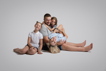 Young family lying on floor and posing on grey studio background