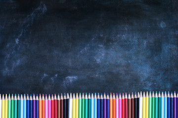 Dusty blank school chalkboard or blackboard and colored pencils with room for copy space.