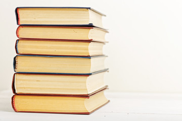 A stack of old books on a light beige background. Copyspace. Angle view.