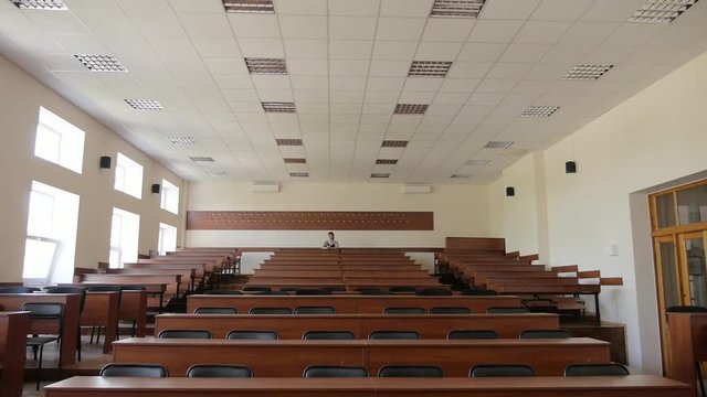 View of the auditorium, lecture hall, in the back row sits a girl student
