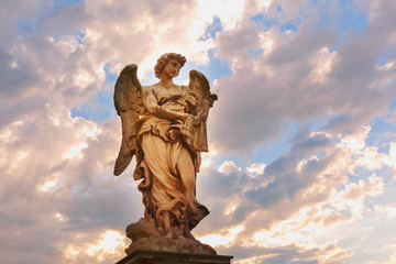 Marble statue of Angel with the Whips at sunset, one of the ten angels on Saint Angel Bridge,...