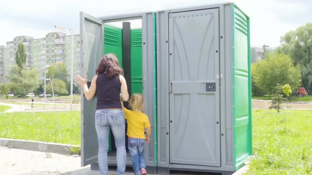 Young woman and little girl attends a street bio-toilet.