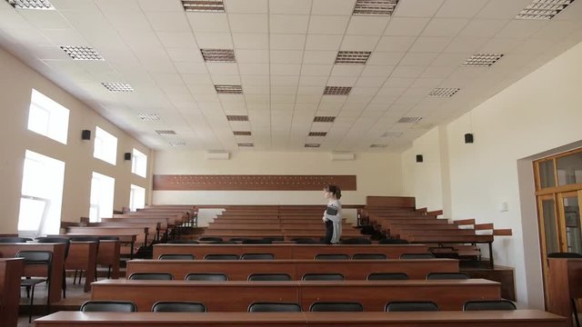 Female student enters to the lecture hall and sits on the back row, before lecture
