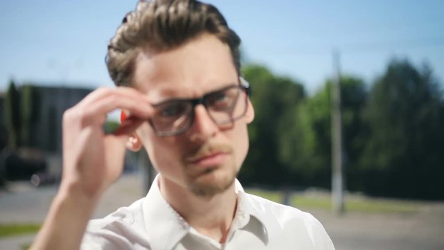 Portrait young man blurred street focused face fix fixing glasses eyeglasses confident moving looking camera attractive handsome trendy hairdo beard thin fashionable stylish serious smiling cool guy