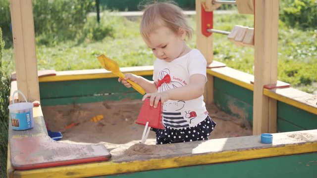 Adorable baby play with sand in sandbox on playground, children kid