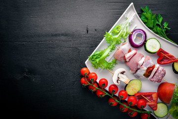 Raw shish kebab and fresh vegetables. On a wooden background. Top view. Freespace for text.