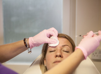 Woman recieving anti-aging injections in her forehead.