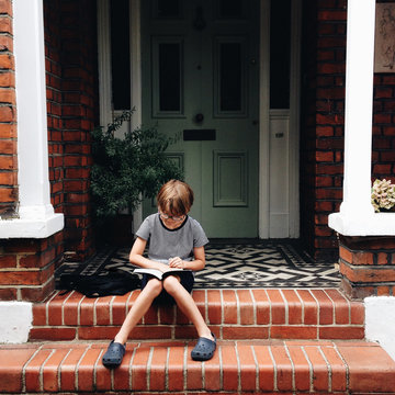 Boy reading by a front door