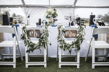 Wedding table under tent, with Mr and Mrs signs on the chairs