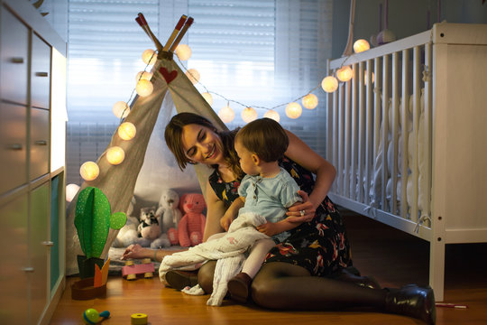 Little girl next to a diy teepee playing with her mother.