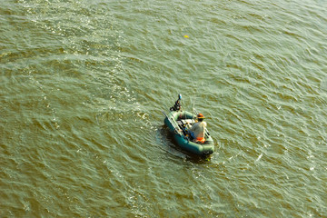 A man in a boat is fishing on the river