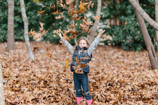 Cute girl throwing leaves around her outside