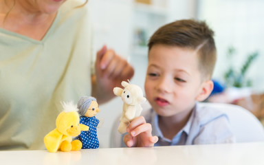 teacher woman playing with child boy with finger puppets in the classroom