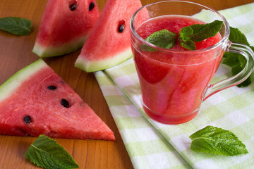 Smoothie from watermelon on the green napkin on the brown wooden background   