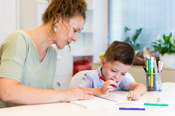 teacher woman drawing with child boy in a classroom