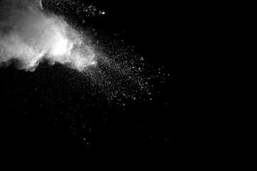 Freeze motion of white dust explosion on black background. Stopping the movement of white powder on dark background. Explosive powder white on black background.