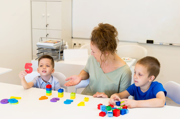 Fototapeta premium teacher woman learn two preschooler boy to count