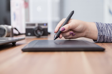 Fototapeta premium Hands of female designer in office working with digital graphic tablet . Creative people or advertising business concept