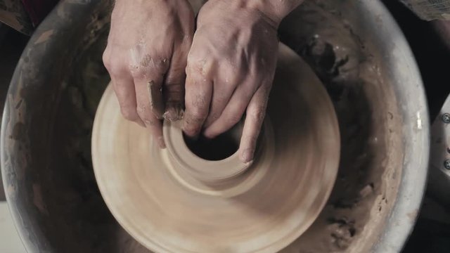Hands of the master potter and vase of clay on the potter's wheel close-up. Master crock man. Twisted potter's wheel.