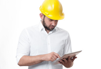 Contractor in yellow builder helmet working on a project with tablet.