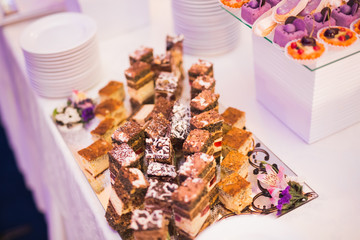 Delicious and tasty dessert table with cupcakes shots at reception closeup