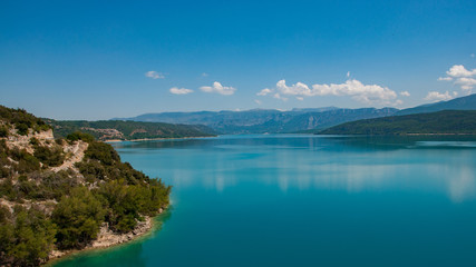 Lac de haute montagne avec plage et ciel bleu se reflétant dans une eau bleue turquoise en forme de carte postale