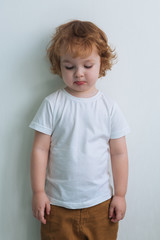 little sad boy in white t shirt isolated on white