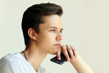 Thoughtful young man with with mobile in hand