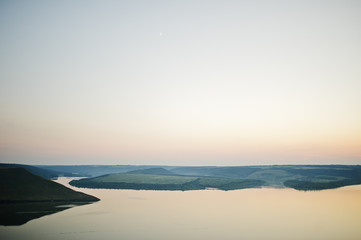 Breathtaking view of a lake surrounded by mountains andd hills.