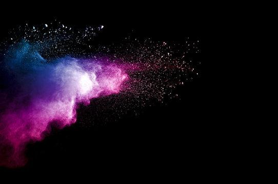 Abstract art colored powder on black background. Frozen abstract movement of dust explosion multiple colors on black background. Stop the movement of multicolored powder on dark background.