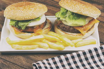 Tasty homemade burger served with fries on plate on a table. Food. Horizontal studio shot.