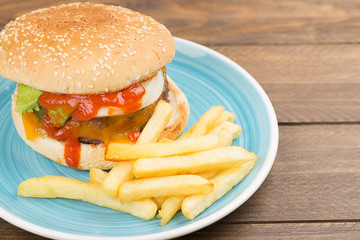 Tasty homemade burger served with fries on plate on a table. Copy space.