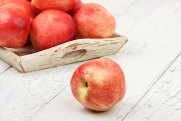 Ripe red peaches in the tray on the white wooden table
